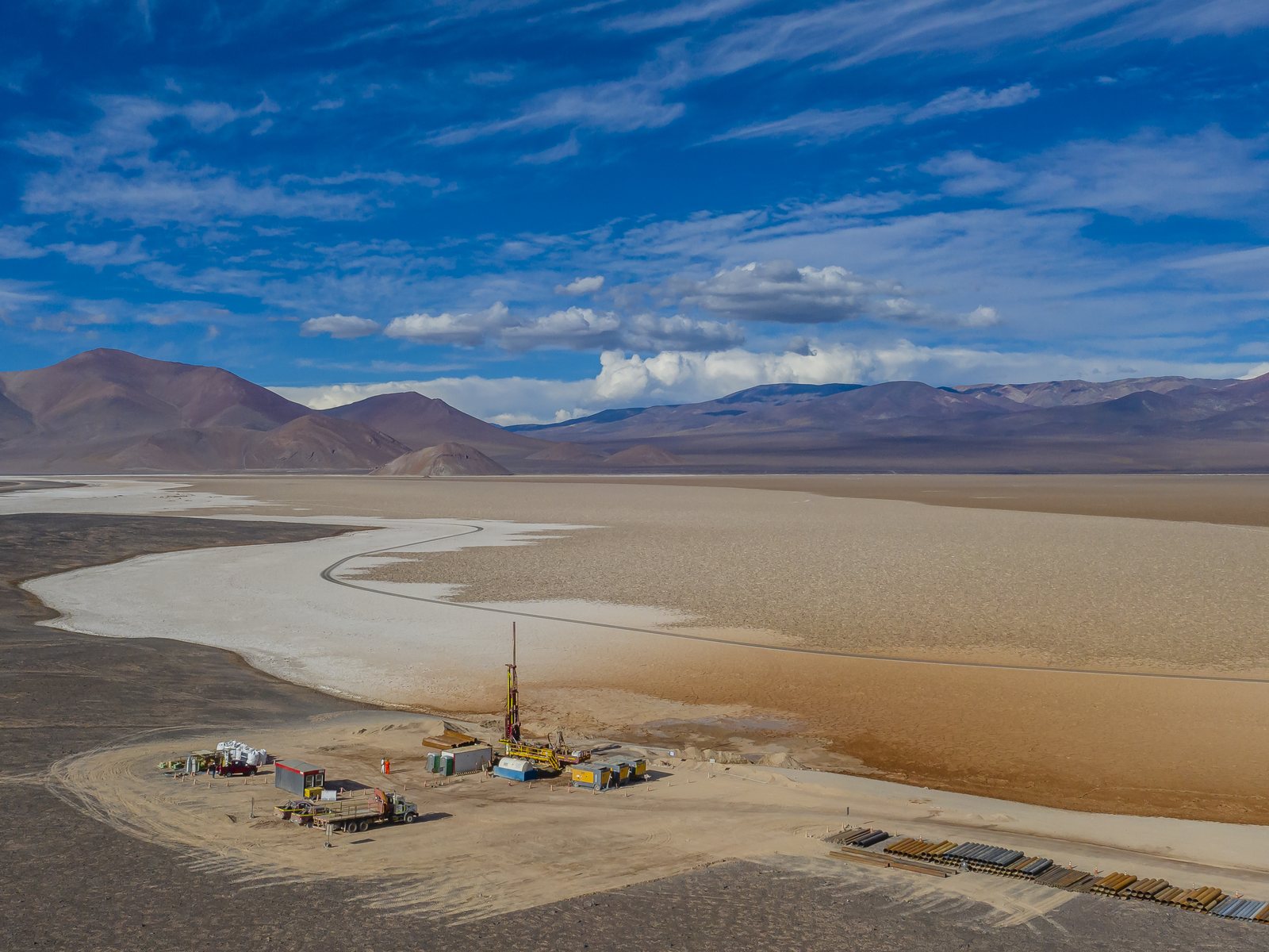 Plataforma de perforación montada al borde de un salar de altura, con accesos y acopio de camisa / Drilling platform set up at the edge of a high-altitude salt flat, with access roads and casing stockpile